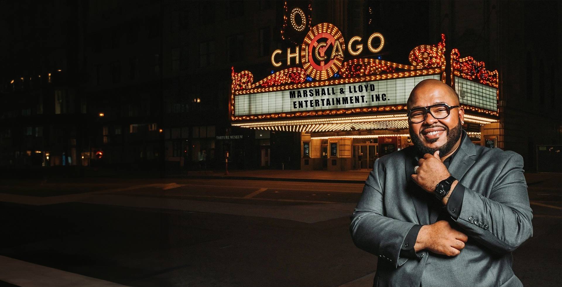 A man standing in front of the chicago theatre.